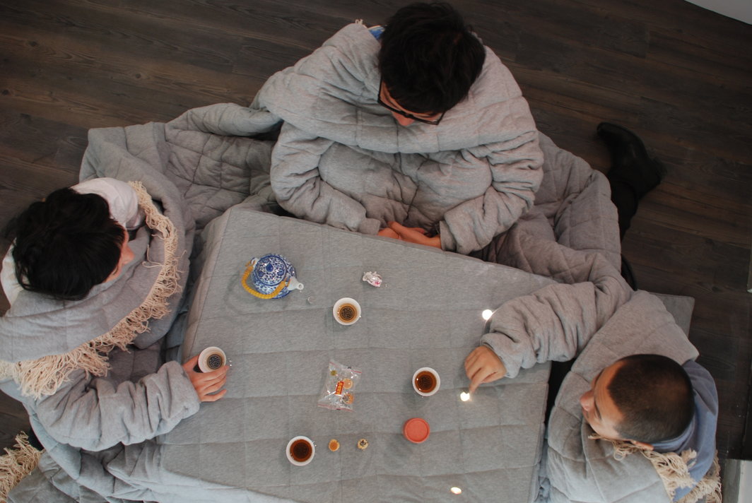 设计师在《何物，何时，何地》的现场穿上他们的设计作品《Kotatsu With Sleeves》用茶。
