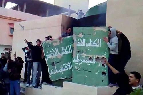2011年2月17日，利比亚港口城市托布鲁克，反对派示威者推倒一面卡扎菲《绿皮书》的纪念墙。
