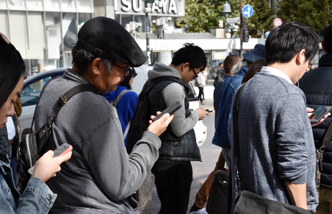 东京涉谷十字路口刷手机等待红灯的行人. 图片来源：AFP.