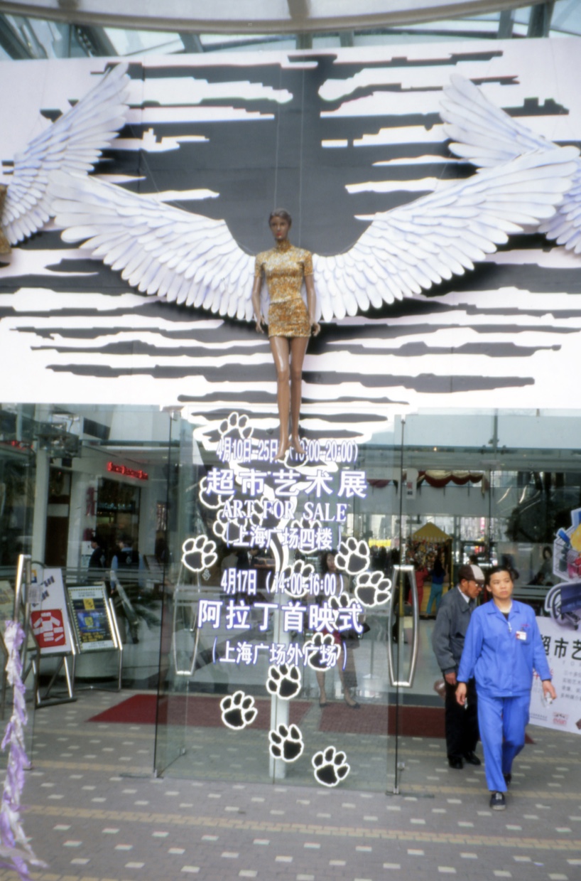 1999年超市展告示牌上方刚巧是一位正面迎向历史废墟的天使. 图片来源：弗兰（Francesca Dal Lago）.